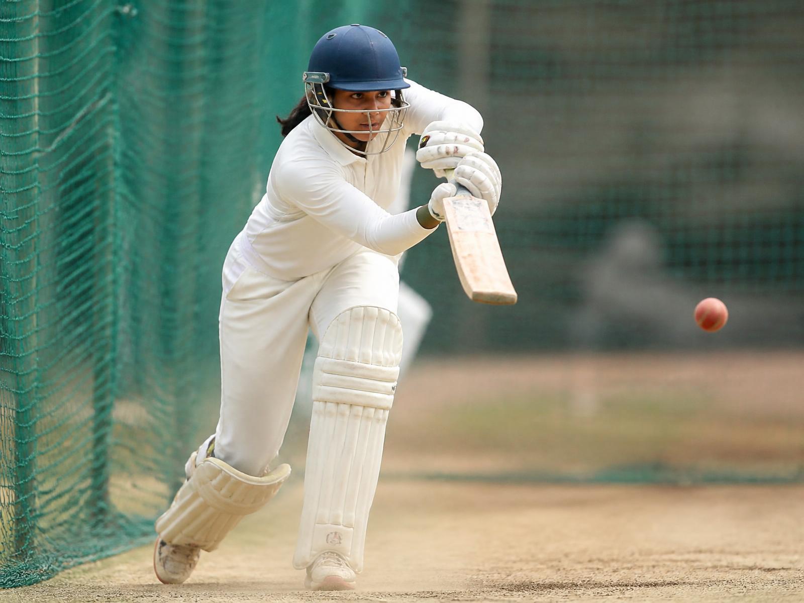 Young woman cricketer batting in practice nets